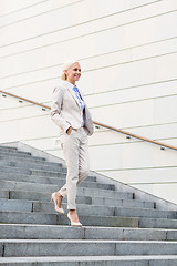 Image showing young smiling businesswoman walking down stairs