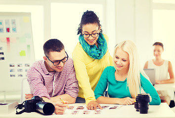 Image showing smiling team with printed photos working in office