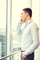 Image showing smiling businessman with smartphone in office