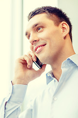 Image showing smiling businessman with smartphone in office