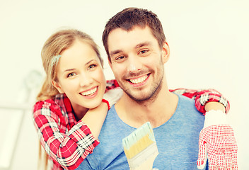 Image showing smiling couple covered with paint with paint brush