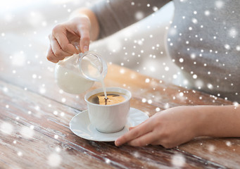 Image showing close up of female pouring milk into coffee cup