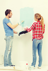 Image showing smiling couple painting wall at home