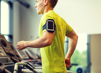 Image showing man with smartphone exercising on treadmill in gym