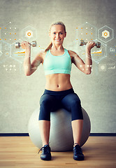 Image showing smiling woman with dumbbells and exercise ball