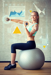 Image showing smiling woman with dumbbells and exercise ball