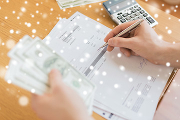 Image showing close up of man counting money and making notes