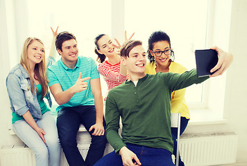 Image showing smiling students making picture with tablet pc