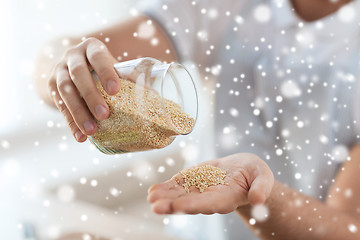 Image showing close up of male emptying jar with quinoa