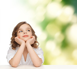 Image showing beautiful girl sitting at table and looking up