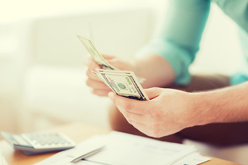 Image showing close up of man counting money and making notes