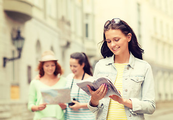 Image showing smiling teenage girls with city guides and camera