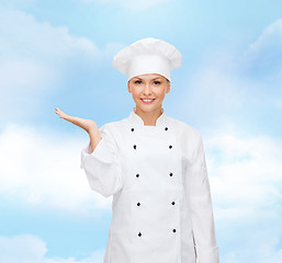 Image showing smiling female chef holding something on hand