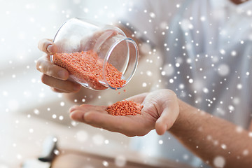 Image showing close up of man emptying jar with red lentils