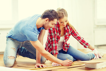 Image showing smiling couple measuring wood flooring