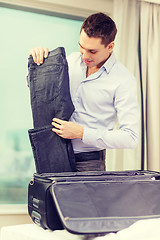 Image showing businessman packing things in suitcase