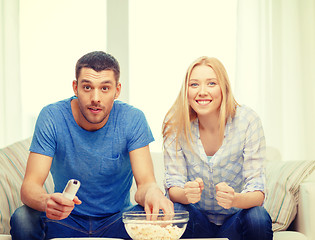 Image showing smiling couple with popcorn cheering sports team