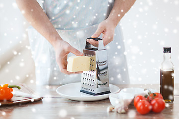 Image showing close up of male hands with grater grating cheese