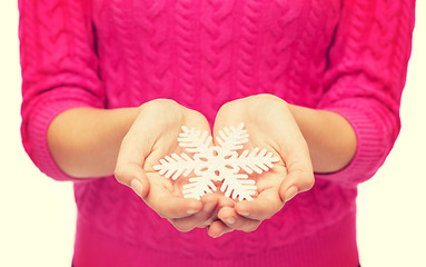 Image showing close up of woman in sweater holding snowflake