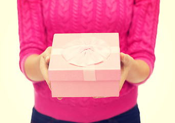 Image showing close up of woman in pink sweater holding gift box