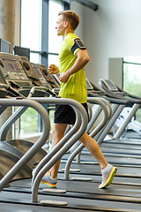 Image showing man with smartphone exercising on treadmill in gym