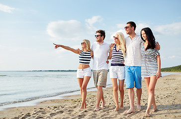 Image showing smiling friends in sunglasses walking on beach