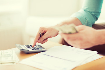 Image showing close up of man counting money and making notes