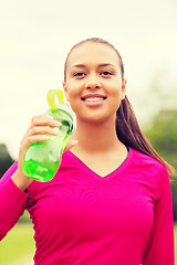 Image showing smiling woman drinking from bottle