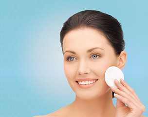 Image showing smiling woman cleaning face skin with cotton pad