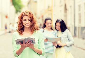 Image showing smiling teenage girls with city guides and camera