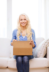 Image showing smiling young woman opening cardboard box