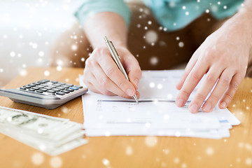 Image showing close up of man counting money and making notes