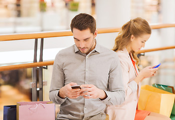 Image showing couple with smartphones and shopping bags in mall