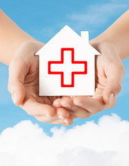 Image showing hands holding paper house with red cross