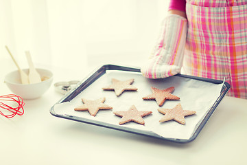 Image showing close up of woman with cookies on oven tray