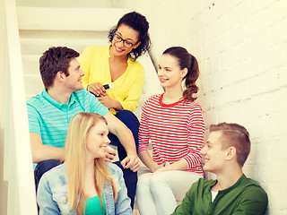 Image showing smiling students with smartphone having discussion