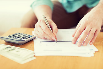 Image showing close up of man counting money and making notes