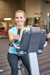 Image showing smiling woman exercising on exercise bike in gym