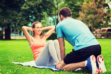 Image showing smiling woman doing exercises on mat outdoors