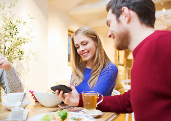 Image showing smiling couple with smartphones meeting at cafe