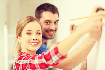 Image showing smiling couple measuring wall