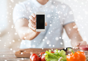 Image showing close up of man showing smartphone in kitchen