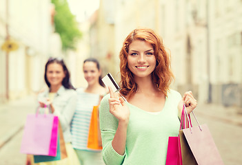 Image showing smiling teenage girls with shopping bags on street