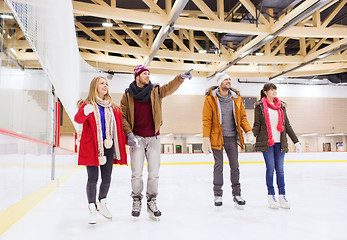 Image showing happy friends pointing finger on skating rink