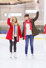 Image showing happy girls friends waving hands on skating rink