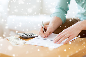 Image showing close up of man counting money and making notes