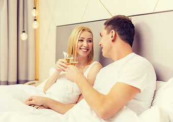 Image showing smiling couple with champagne glasses in bed