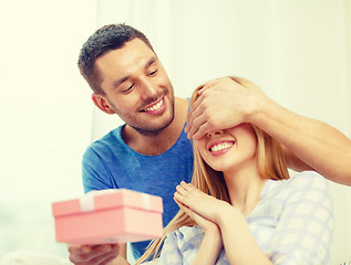 Image showing smiling man surprises his girlfriend with present