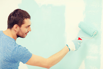 Image showing smiling man painting wall at home