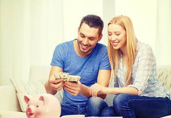 Image showing smiling couple counting money at home